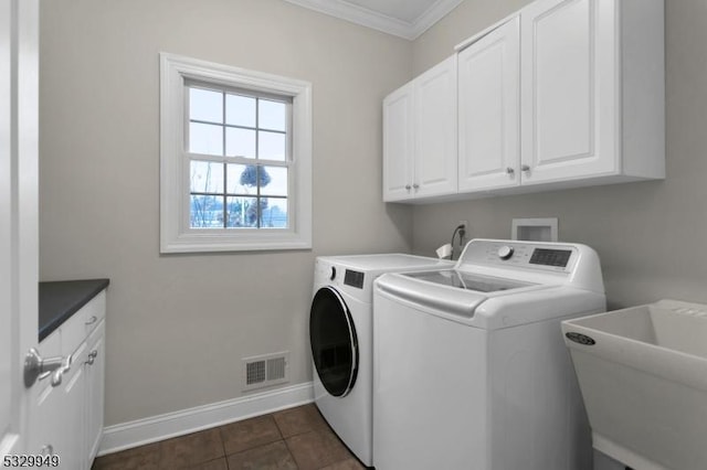 clothes washing area with sink, crown molding, cabinets, washer and dryer, and dark tile patterned floors