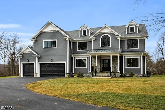 view of front of home with central AC unit, a garage, covered porch, and a front lawn