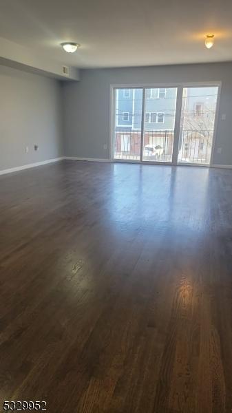 spare room with a healthy amount of sunlight and dark wood-type flooring