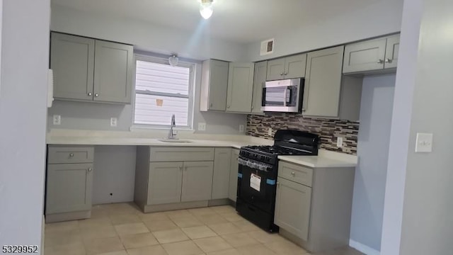 kitchen featuring gray cabinetry, decorative backsplash, gas stove, and sink