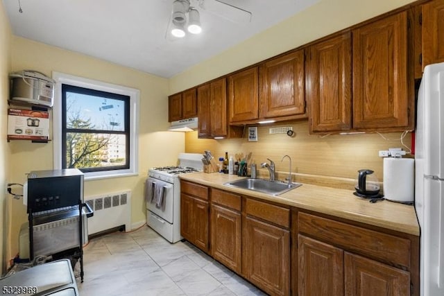 kitchen with ceiling fan, radiator heating unit, white appliances, and sink