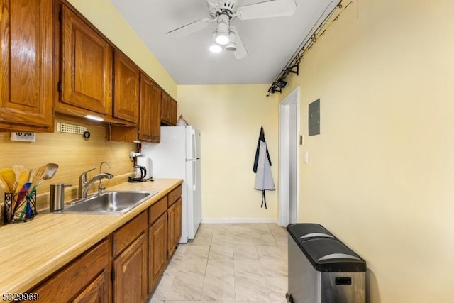 kitchen featuring white refrigerator, electric panel, ceiling fan, and sink