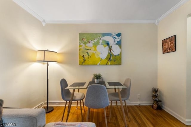 dining space with hardwood / wood-style flooring and crown molding