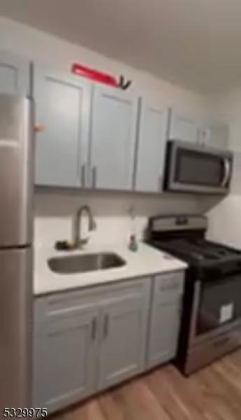 kitchen featuring stainless steel fridge, light hardwood / wood-style floors, sink, and black / electric stove