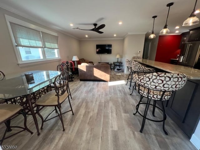 dining area with ceiling fan, crown molding, and light hardwood / wood-style flooring