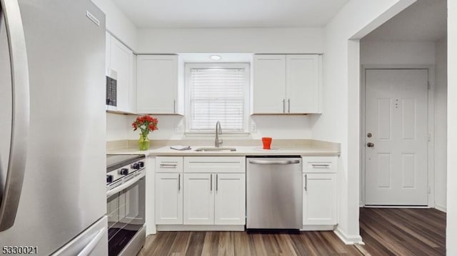 kitchen with appliances with stainless steel finishes, dark hardwood / wood-style flooring, white cabinetry, and sink