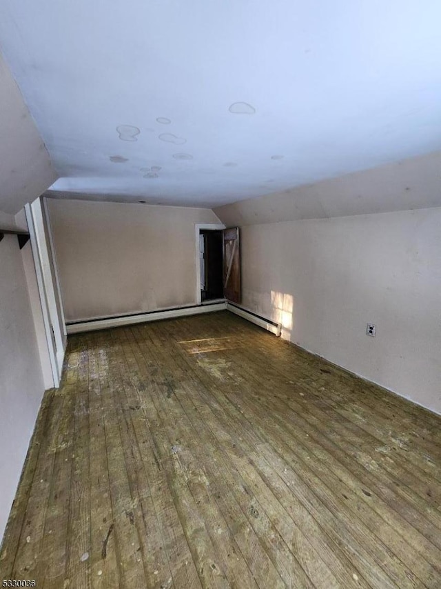 empty room with dark wood-type flooring, lofted ceiling, and a baseboard heating unit