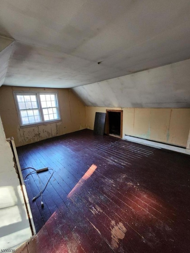 additional living space featuring vaulted ceiling, dark hardwood / wood-style floors, and a baseboard heating unit