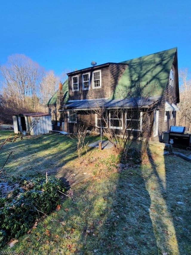 rear view of house featuring a storage shed and a lawn