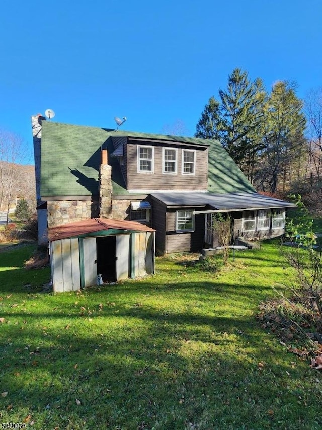 back of property with a lawn and a shed