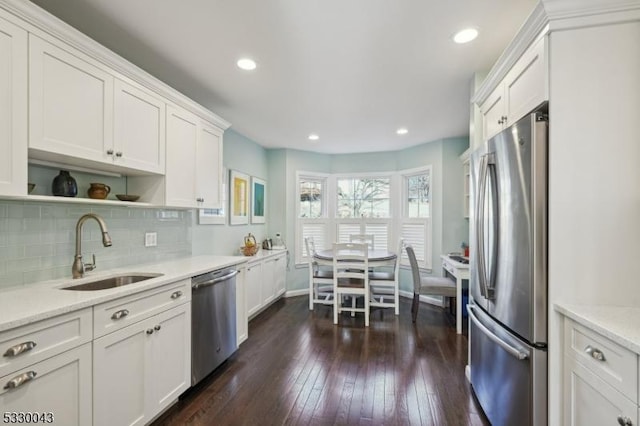 kitchen featuring dark wood-style flooring, stainless steel appliances, backsplash, white cabinets, and a sink