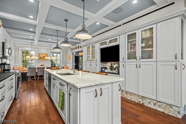 kitchen featuring coffered ceiling, a center island with sink, white cabinets, sink, and stainless steel appliances