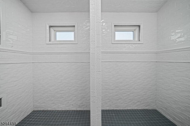 bathroom with a healthy amount of sunlight and tiled shower