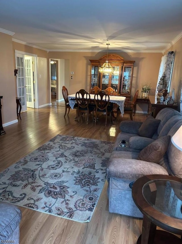 living room featuring wood-type flooring, ornamental molding, and a notable chandelier