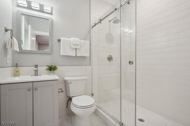 bathroom with marble finish floor, vanity, a shower stall, and toilet