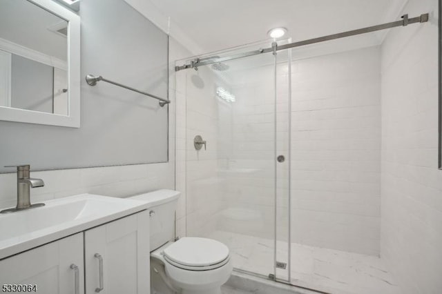 bathroom with tile walls, a shower stall, toilet, and vanity