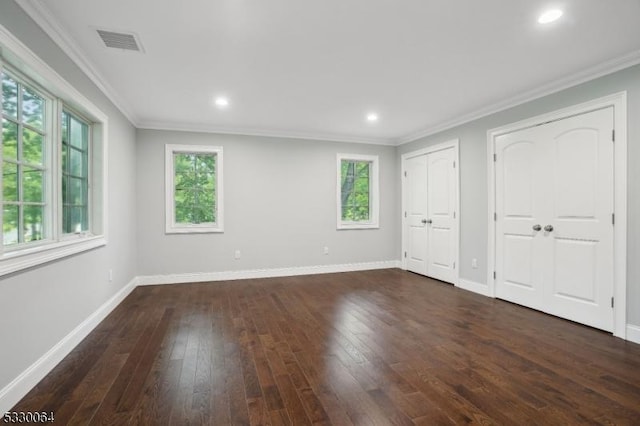 unfurnished bedroom featuring ornamental molding, dark wood-style flooring, baseboards, and two closets