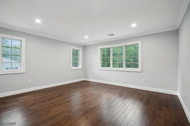 empty room featuring crown molding, a wealth of natural light, visible vents, dark wood-type flooring, and baseboards