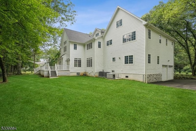 rear view of property featuring central AC, a yard, driveway, and an attached garage