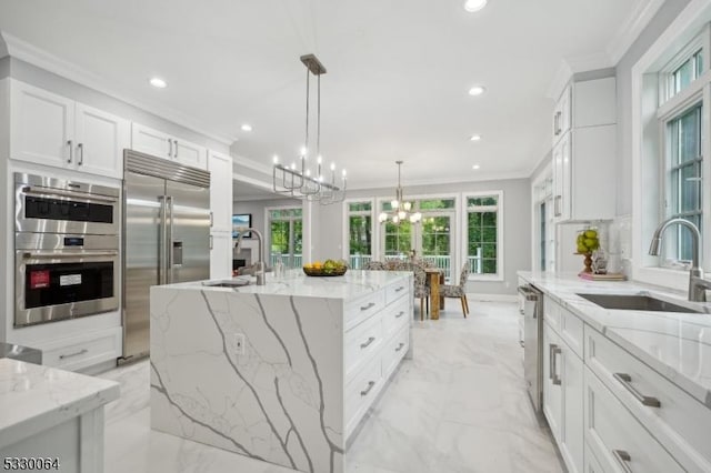 kitchen with marble finish floor, appliances with stainless steel finishes, a sink, and crown molding