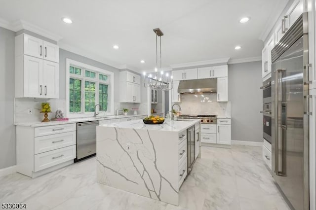 kitchen featuring marble finish floor, appliances with stainless steel finishes, ornamental molding, white cabinetry, and under cabinet range hood