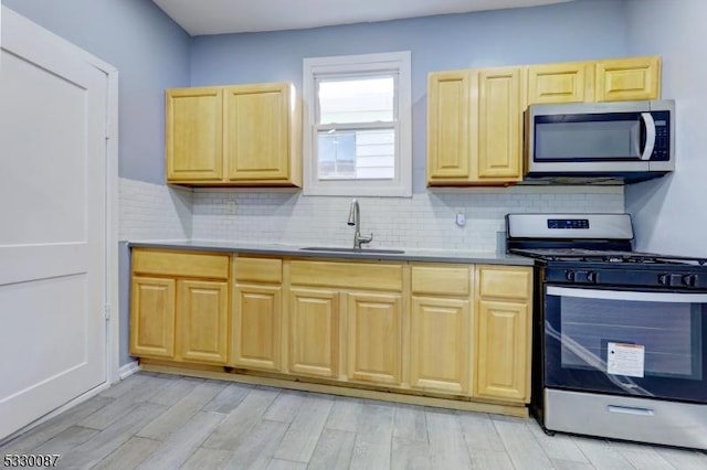 kitchen with light wood-type flooring, stainless steel appliances, tasteful backsplash, and sink