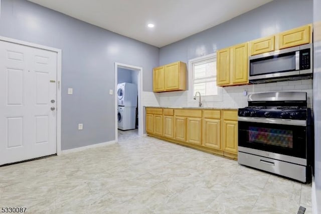 kitchen featuring sink, light brown cabinets, tasteful backsplash, stacked washer and dryer, and appliances with stainless steel finishes