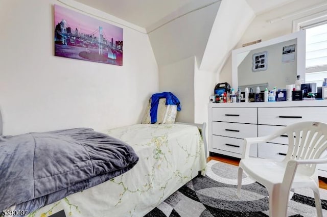 bedroom with wood-type flooring and vaulted ceiling