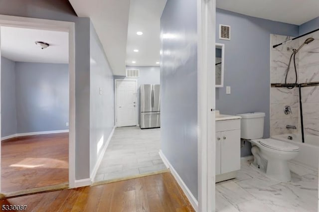 full bathroom with hardwood / wood-style floors, vanity, toilet, and tiled shower / bath