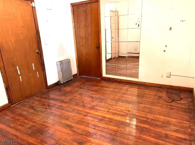 empty room featuring radiator and hardwood / wood-style flooring