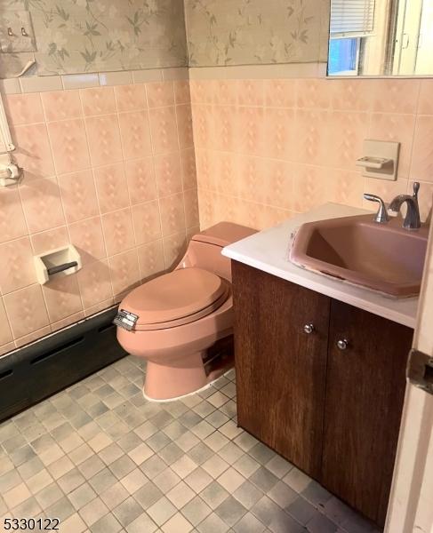 bathroom featuring tile patterned flooring, vanity, toilet, and tile walls