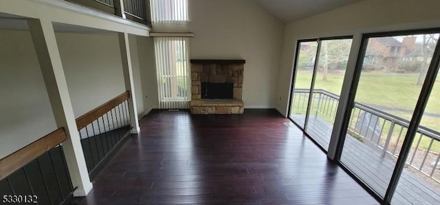 unfurnished living room with dark hardwood / wood-style floors, a stone fireplace, and lofted ceiling