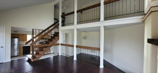 stairs with hardwood / wood-style floors, a towering ceiling, and a chandelier