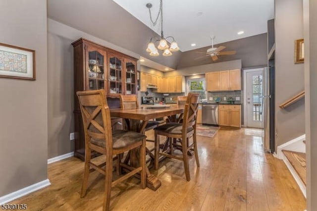 dining area featuring light wood-type flooring, ceiling fan with notable chandelier, and lofted ceiling