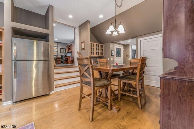 dining space featuring light wood-type flooring, lofted ceiling, and an inviting chandelier