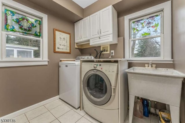 washroom featuring washing machine and clothes dryer, plenty of natural light, light tile patterned floors, and cabinets