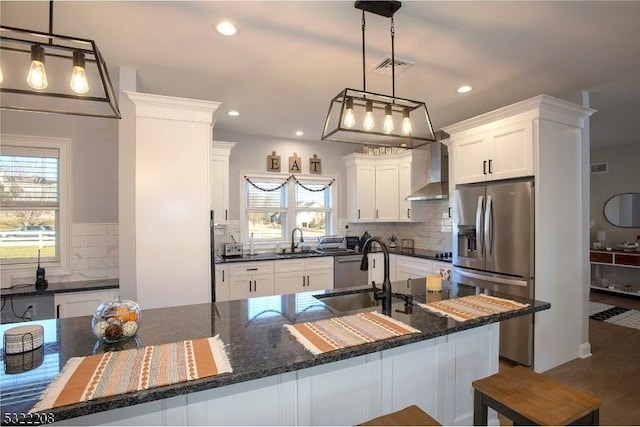 kitchen featuring white cabinetry, stainless steel fridge, sink, and wall chimney range hood