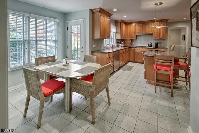 kitchen featuring stainless steel dishwasher, hanging light fixtures, light tile patterned floors, tasteful backsplash, and sink