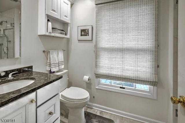 bathroom with a shower with door, vanity, and toilet