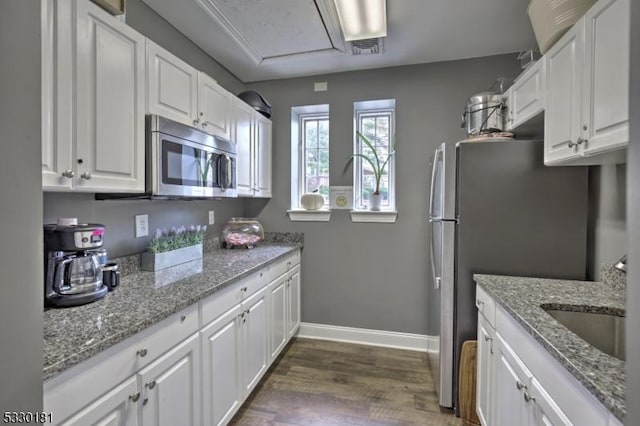 kitchen featuring dark wood-type flooring, light stone countertops, stainless steel appliances, white cabinets, and sink