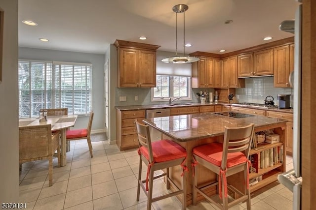 kitchen with hanging light fixtures, a center island, light tile patterned floors, a wealth of natural light, and sink