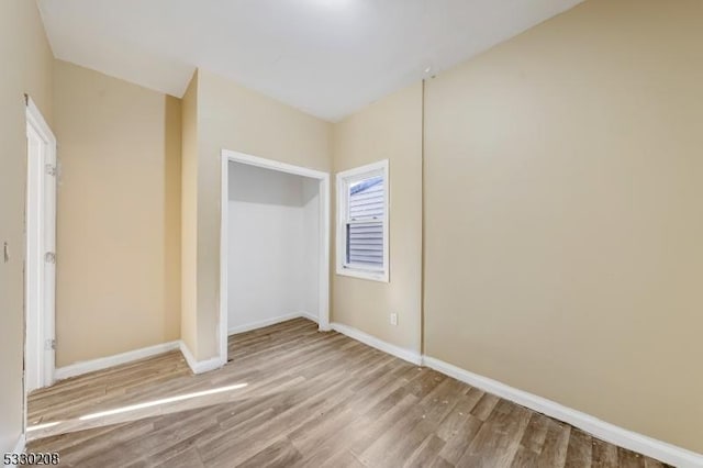 unfurnished bedroom with light wood-type flooring and a closet