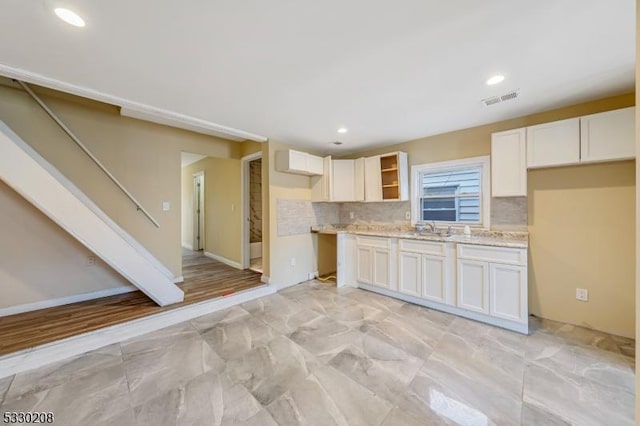 kitchen featuring tasteful backsplash, sink, and white cabinets