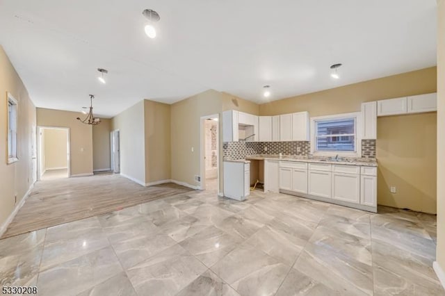 kitchen with white cabinets, a chandelier, sink, and tasteful backsplash