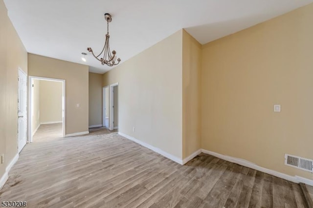 spare room featuring light hardwood / wood-style flooring and an inviting chandelier