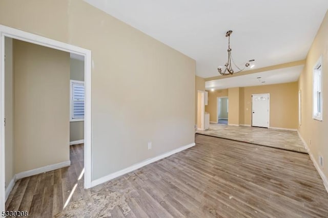 unfurnished living room with hardwood / wood-style floors and a notable chandelier