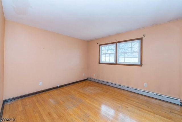 empty room with light wood-type flooring and a baseboard heating unit