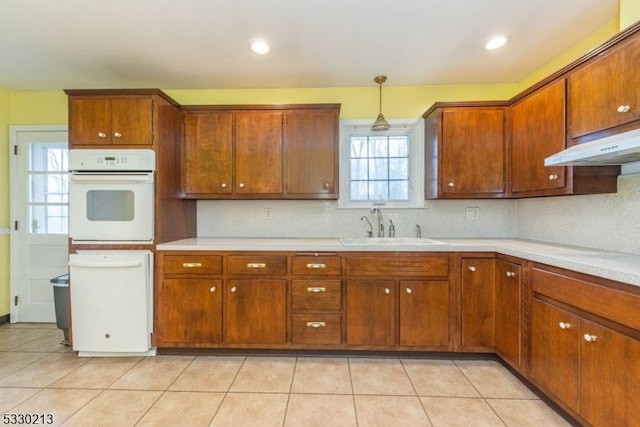 kitchen featuring white oven, backsplash, sink, and pendant lighting