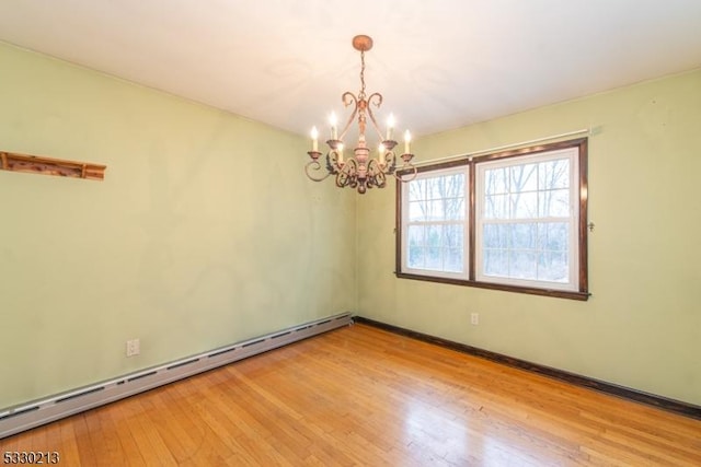 empty room with hardwood / wood-style flooring, an inviting chandelier, and a baseboard radiator