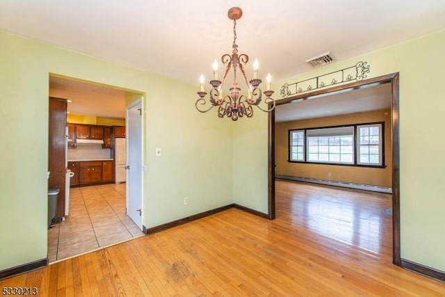 unfurnished dining area with baseboard heating, light hardwood / wood-style flooring, and an inviting chandelier